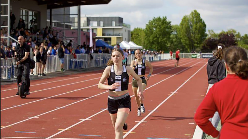 relais d'athlétisme, sur un circuit ovale, avec un sol rouge et des gradins pleins